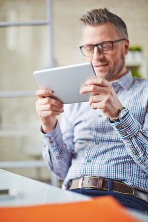 Businessman with digital tablet spending free time in officeの写真素材