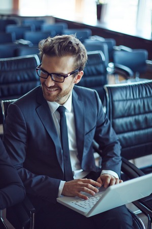 Male employee typing while listening to colleague at meeting