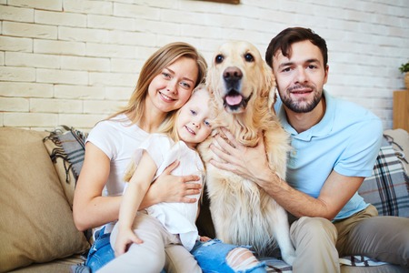 Modern family and their cute pet resting at homeの写真素材