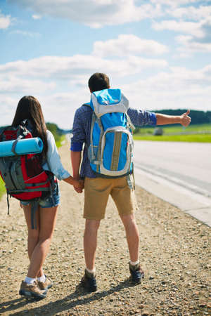 Rear view of hitch-hiking couple with rucksacksの写真素材