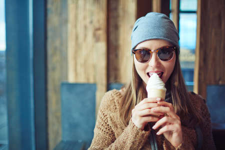 Stylish girl eating ice-cream in cafe