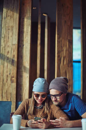 Modern couple with smartphone having rest in cafeの写真素材