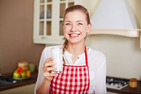 Happy and healthy woman with glass of kefir looking at cameraの写真素材