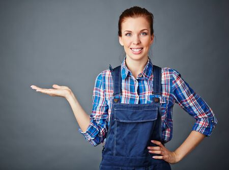 Happy young woman in coveralls keeping her palm openの写真素材