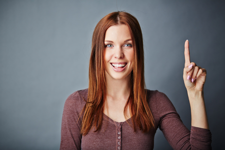 Happy young woman keeping her forefinger raised upwardsの写真素材
