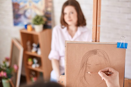 Human hand with crayon drawing young woman in studioの写真素材
