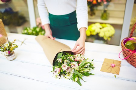 Female florist wrapping up bouquet of white amaryllisesの写真素材
