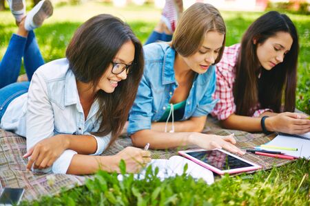 Modern teen girls doing schoolwork outside
