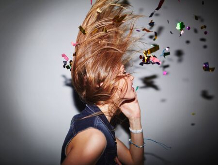 Energetic female dancer with confetti having fun in nightclub