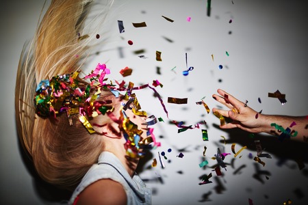 Blond girl dancing in nightclub while man throwing confetti at herの写真素材