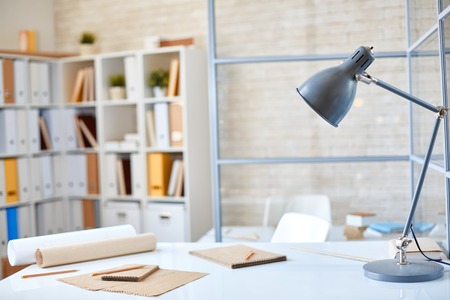 Desk with lamp, papers and pencils in office