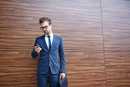 Businessman with briefcase using cellphoneの写真素材