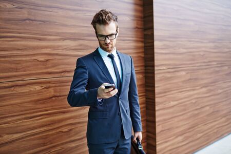 Businessman using cellphone on wooden backgroundの写真素材
