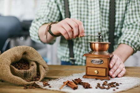 Barista tampering coffee beans in wooden coffee grinderの写真素材