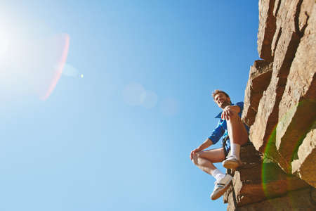 Young traveler sitting on cliff edgeの写真素材
