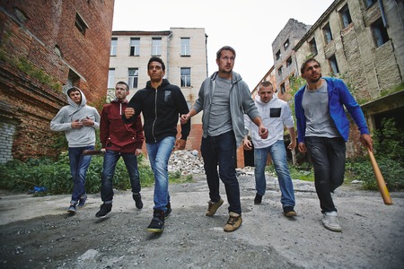 Group of spiteful hooligans walking along grunge brick housesの写真素材