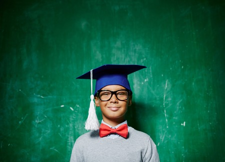 Smiling kid in eyeglasses and graduation hatの写真素材
