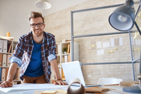 Contemporary engineer looking at camera during work in office