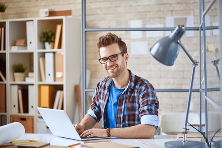Happy businessman looking at camera while networking at workplaceの写真素材
