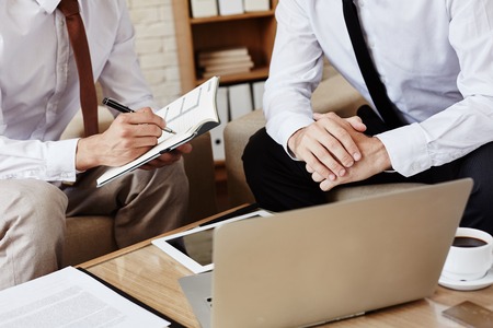 Businessman writing working plan with colleague sitting near byの写真素材