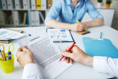 Businessman signing contract in working environmentの写真素材
