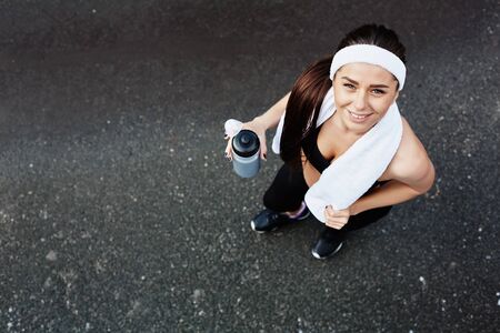 Active girl with bottle of water looking at camera with smileの写真素材