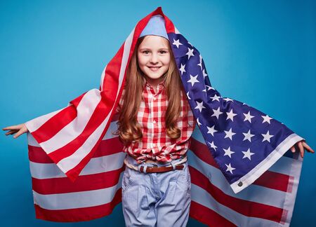 Cheerful girl with flag of USA looking at camera