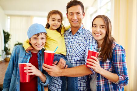 Happy family with coke looking at camera