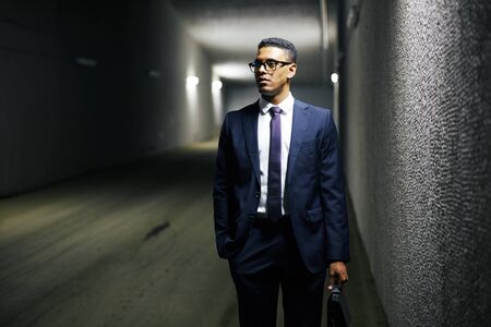 Young businessman with briefcase standing in tunnelの写真素材