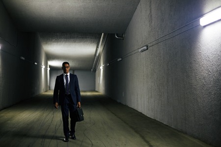 Elegant businessman with briefcase walking down tunnelの写真素材