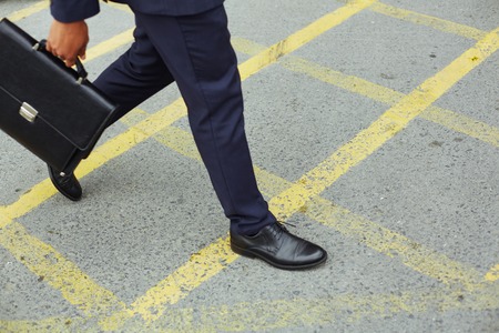 Legs of businessman with briefcase walking down trottoire