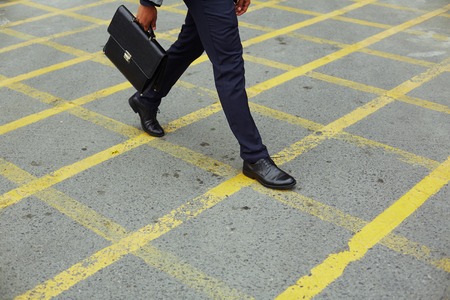 Legs of businessman with briefcase going to workの写真素材