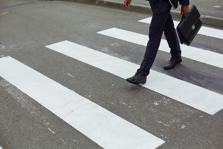 Elegant businessman with briefcase walking down crosswalk