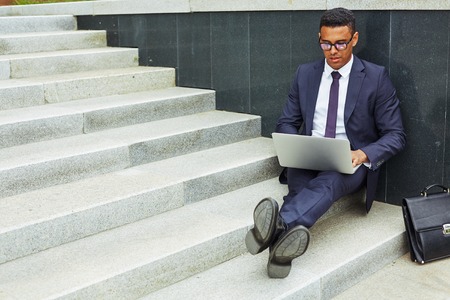 Young businessman using laptop in urban environmentの写真素材