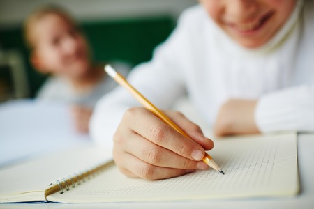 Kid holding pencil and drawing in notepadの写真素材