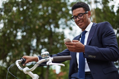 Happy modern businessman using cellphone in parkの写真素材