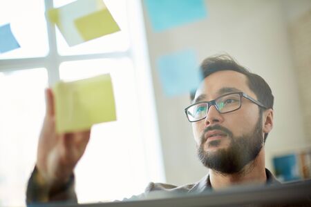 Young modern businessman looking at reminder with working plan
