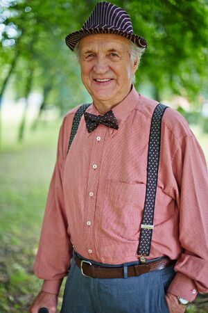 Cheerful senior man in smart casual looking at camera in parkの写真素材