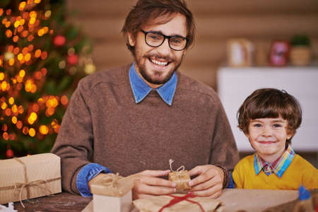 Happy young man and his son with wrapped gifts looking at camera and smilingの写真素材