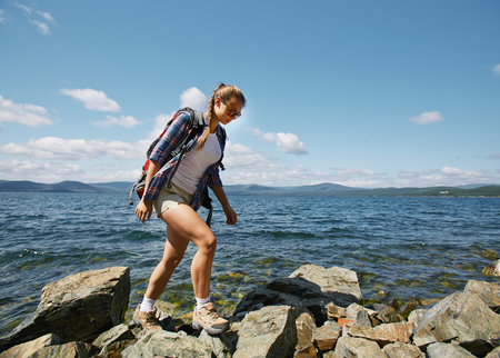 Pretty hiker walking on rocks by the seasideの写真素材