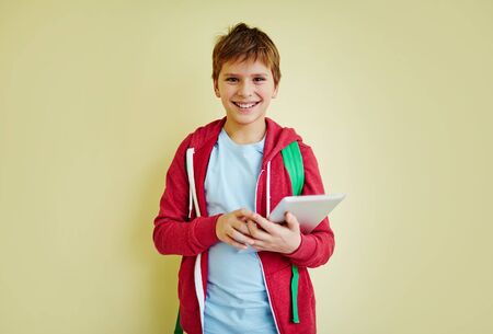 Cute schoolboy with touchpad looking at camera with smileの写真素材