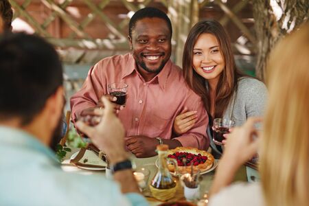 Happy young couple with red wine sitting by Thanksgiving tableの写真素材