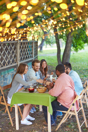 Happy friends eating Thanksgiving dinner outdoorsの写真素材