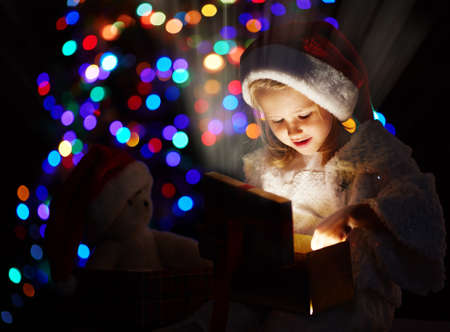 Cute girl holding open giftbox full of bright lightの写真素材