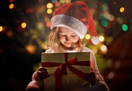Happy girl in Santa cap looking at magic gift in box on xmas nightの写真素材
