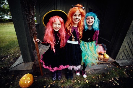 Halloween witches looking at camera by haunted houseの写真素材