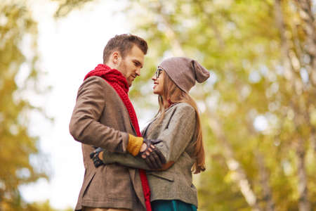 Amorous guy and girl looking at one another during date in parkの写真素材