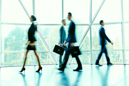 Blurred figures of hurrying employees inside office buildingの写真素材