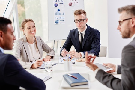 Group of confident colleagues interacting at meeting in officeの写真素材