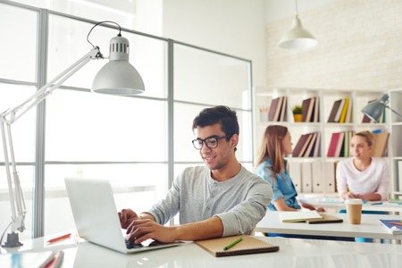 College student typing during break on background of talking girlsの写真素材